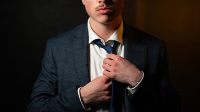 Man looks at camera, fixing his tie, unsettled