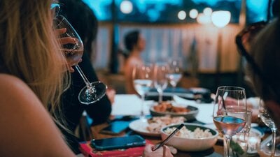 Woman drinking sparkling wine with art model sitting in background