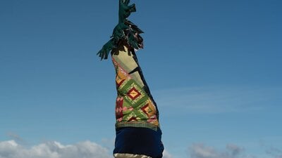 A textile tree sitting on top of a hill. The trunk is with quilts with plush leaves on the top.