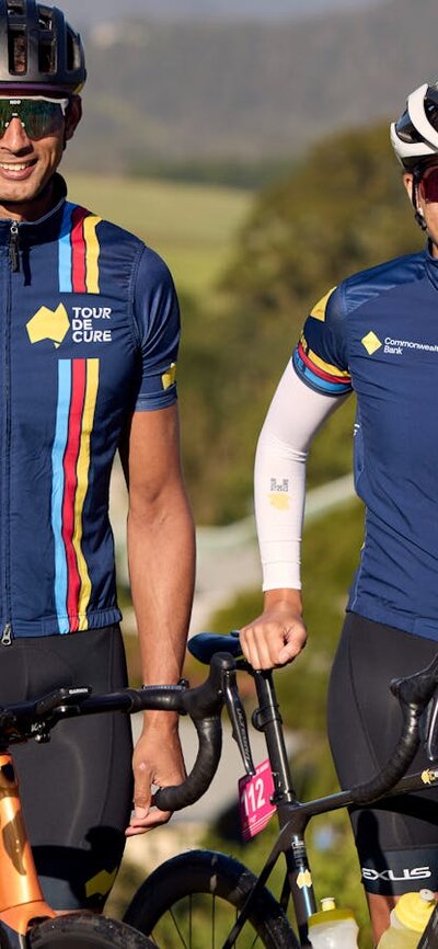 Male and female cyclist standing in scenic background smiling at the camera off-bikes