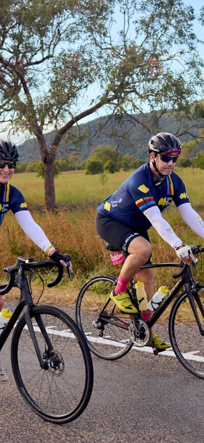 Cyclists riding on the road in a peloton with grass and hills scenic background
