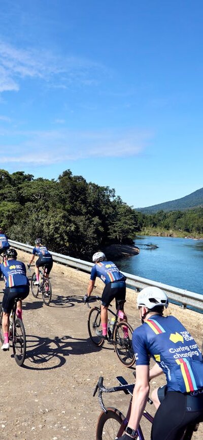Cycle peloton crossing bridge in formation taken from behind cyclists, scenic