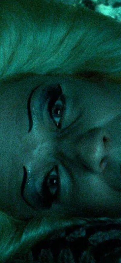 Person tilting head to the side, wearing a wig and vibrant makeup