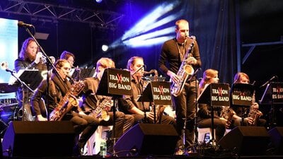 A big band plays on stage, with a soloist standing to play saxophone