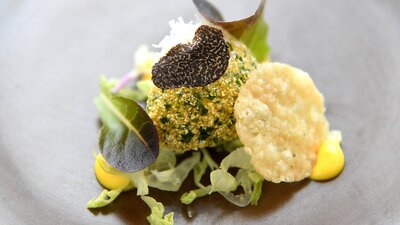 Floriade inspired degustation dinner An image of a black plate with antipasto roulade on a white background.