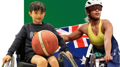 Young boy sitting in a sports wheelchair holding a basketball with a Paralympian next to him