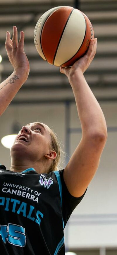 Woman in motion of shooting a basketball.