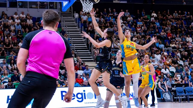UC Capitals player driving to the basket for a layup during a WNBL game.