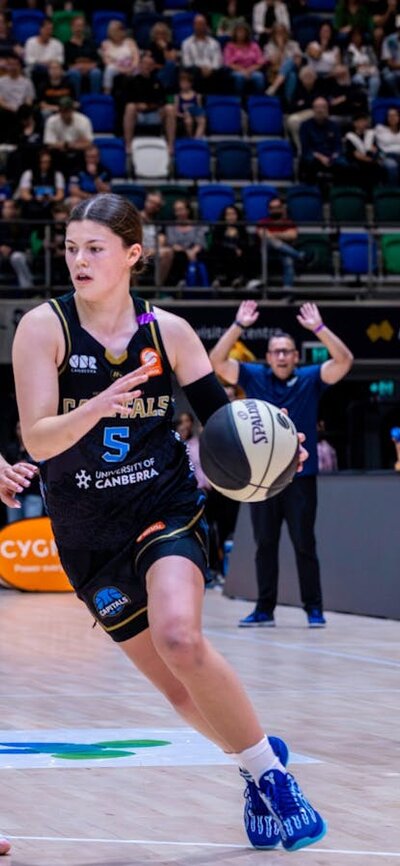 UC Capitals player driving to the basket for a layup during a WNBL game.