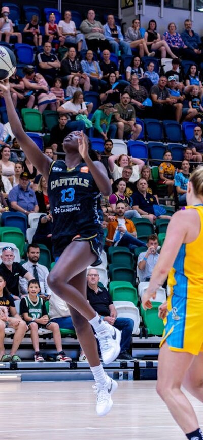 UC Capitals player driving to the basket for a layup during a WNBL game.