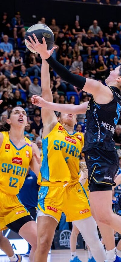 UC Capitals player driving to the basket for a layup during a WNBL game.