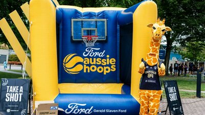 Giraffe mascot in front of a jumping castle.