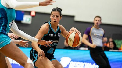 Female basketball player bounces the ball.