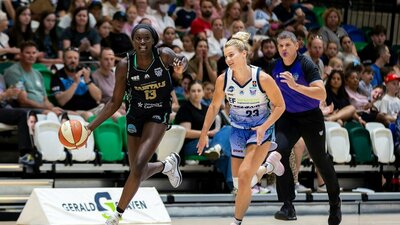 Basketball player runs down the court with defender in tow.