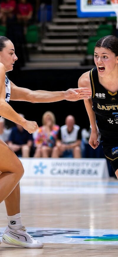 UC Capitals player driving to the basket for a layup during a WNBL game.