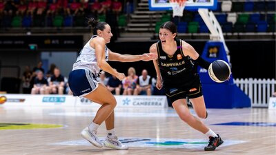 UC Capitals player driving to the basket for a layup during a WNBL game.