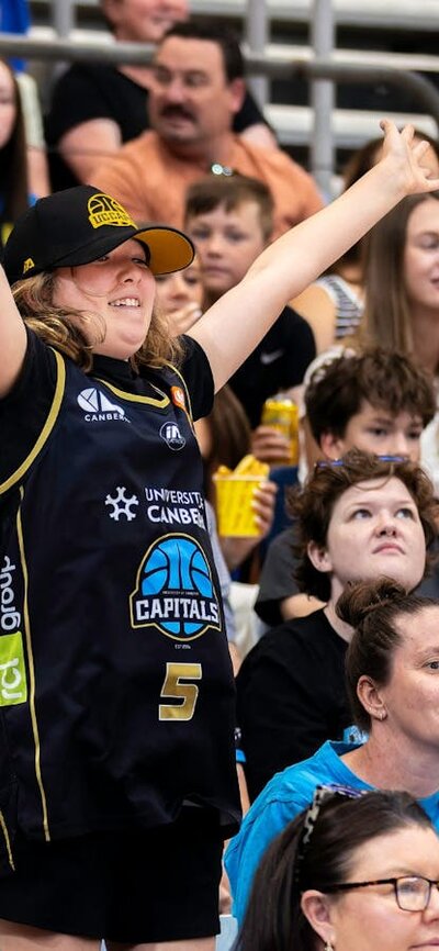 UC Capitals fan jumping and cheering in the crowd wearing Caps merch.