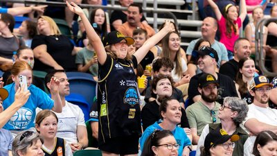 UC Capitals fan jumping and cheering in the crowd wearing Caps merch.