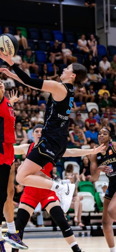UC Capitals player driving to the basket for a layup during a WNBL game.