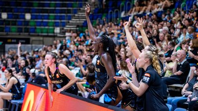 UC Capitals players cheering with their hands up on the player bench.