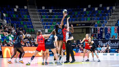 Basketball players mid-jump while competing for the tip-off.