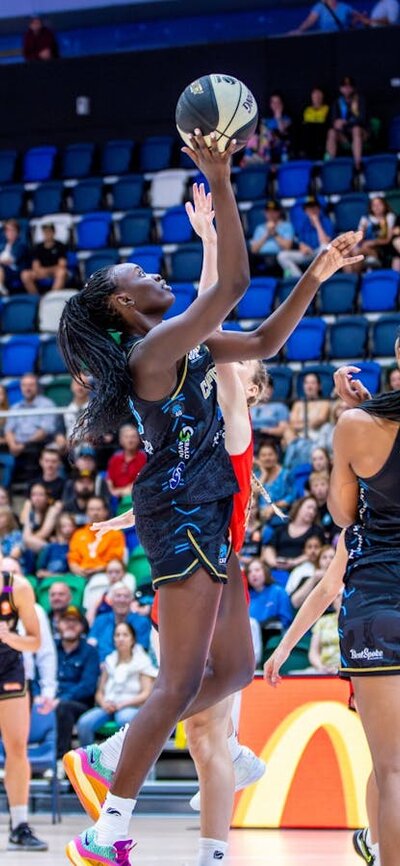 UC Capitals player driving to the basket for a layup during a WNBL game against Perth Lynx.