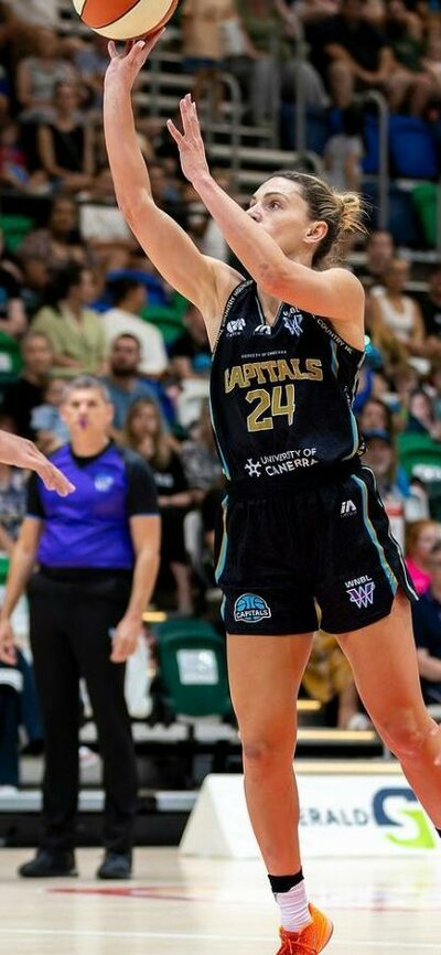 Female basketball player puts up a shot attempt surrounded by opponents.