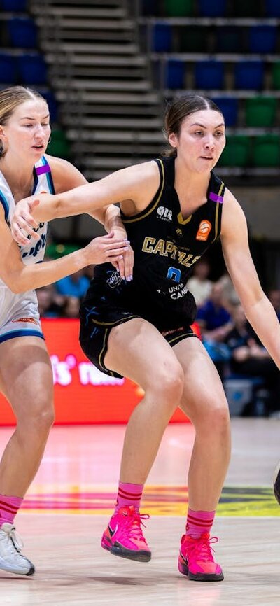 UC Capitals player driving to the basket for a layup during a WNBL game.