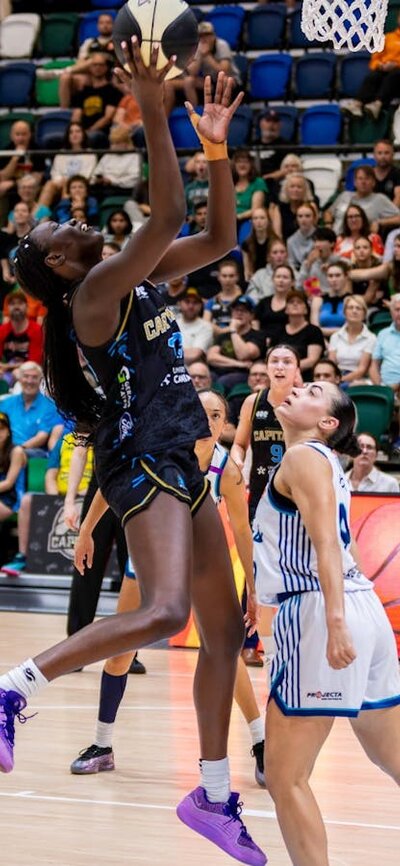 UC Capitals player driving to the basket for a layup during a WNBL game.