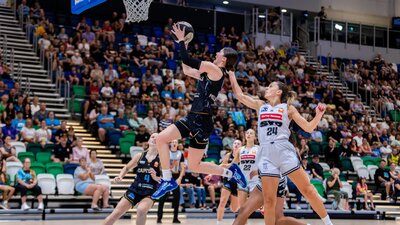 UC Capitals player driving to the basket for a layup during a WNBL game against Sydney Flames.