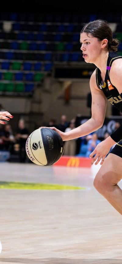 UC Capitals player driving to the basket for a layup during a WNBL game.