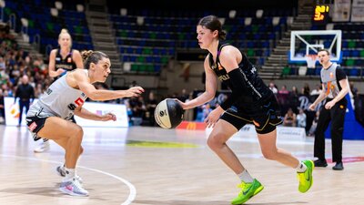 UC Capitals player driving to the basket for a layup during a WNBL game.