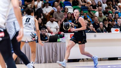 UC Capitals player dribbling a basketball while being defended.