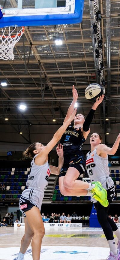 UC Capitals player driving to the basket for a layup during a WNBL game.