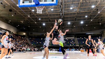 UC Capitals player driving to the basket for a layup during a WNBL game.