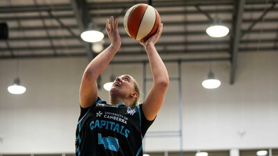 Woman in motion of shooting a basketball.