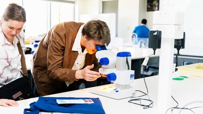 A prospective student looking through a microscope in one of the many scientific laboratories