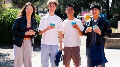 Four students holding large blue donuts