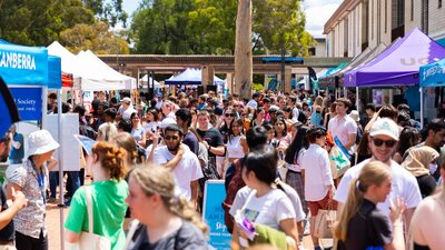 Busy university concourse filled with marquees and people on a sunny open day