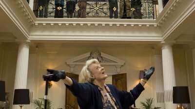 Woman stands happy looking up towards people on a balcony