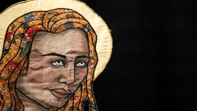Tal Fitzpatrick | Quietly Seething: Fate, Fury and Transmutation A close up of a quiltyed textile artwork showing a womans face with a yellow halo behind her head