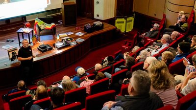 Vinyl Lounge Reconciliation Week 2025 Audience in a theatre and a man at the front preparing to play a vinyl