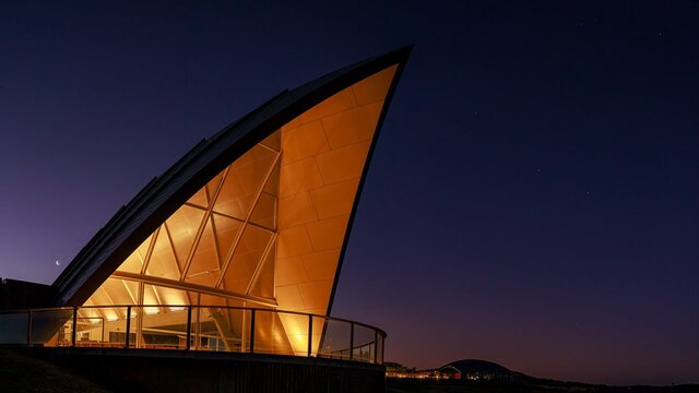 The triangular roof of the Margaret Whitlam Pavilion lights up against an evening sky