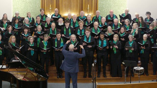 CCS Songs of Open Country concert 4 Oct 2025 Choristers performing in front of altar, Dan Walker conducting, grand piano to his left.