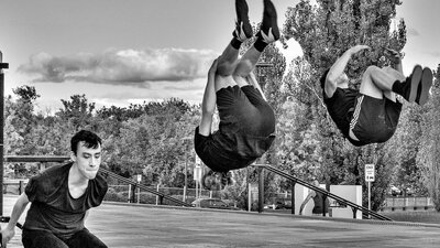 Learn Acrobatics at Warehouse Circus these ACT school holidays 3 young men perform a backsault.