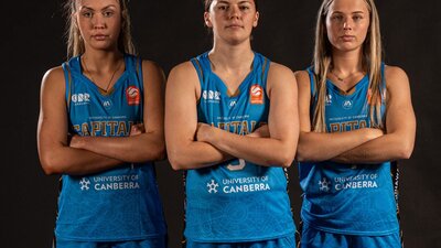 Three basketball players wearing blue jerseys with arms folded.