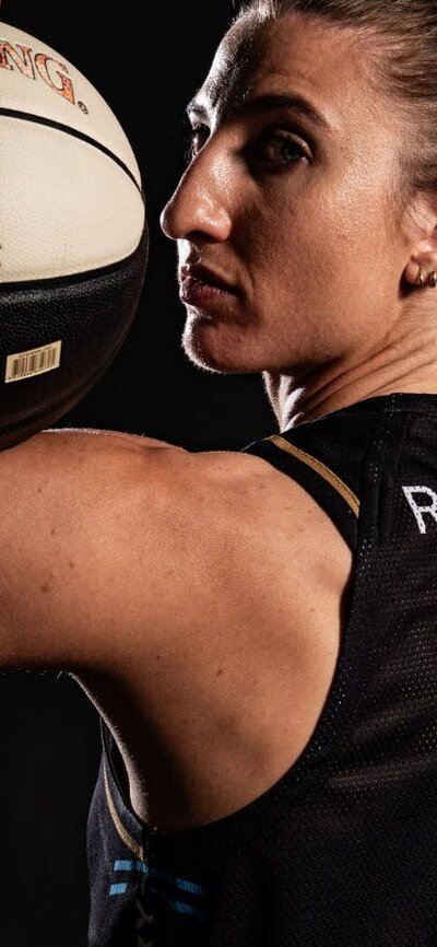 Basketball player holds a ball on her shoulder.