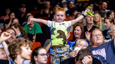 Child stands on a seat cheering and waving.