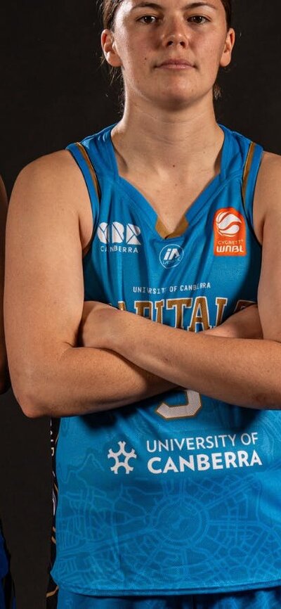 Three UC Capitals players in blue jerseys standing with arms crossed.