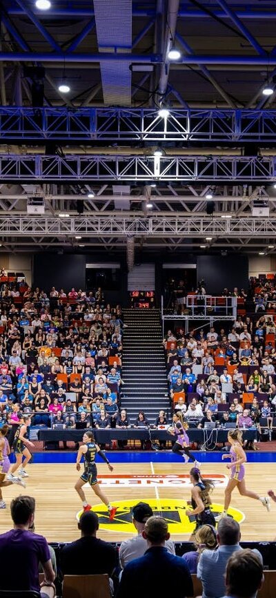 Indoor basketball court with a stadium of spectators.